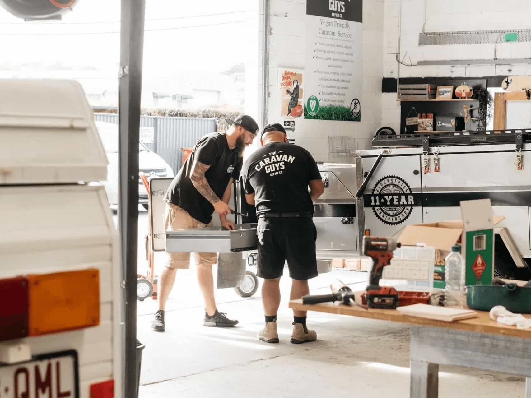 Technicians working on a caravan drawer system in workshop.