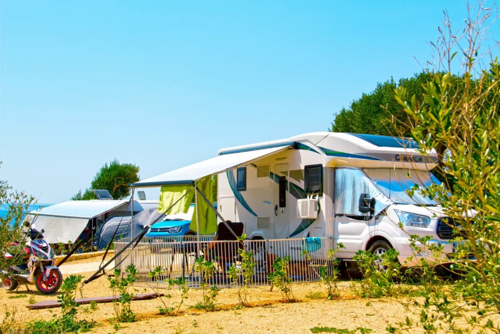 Caravan at the beach on a sunny day with an awning attached to the side.